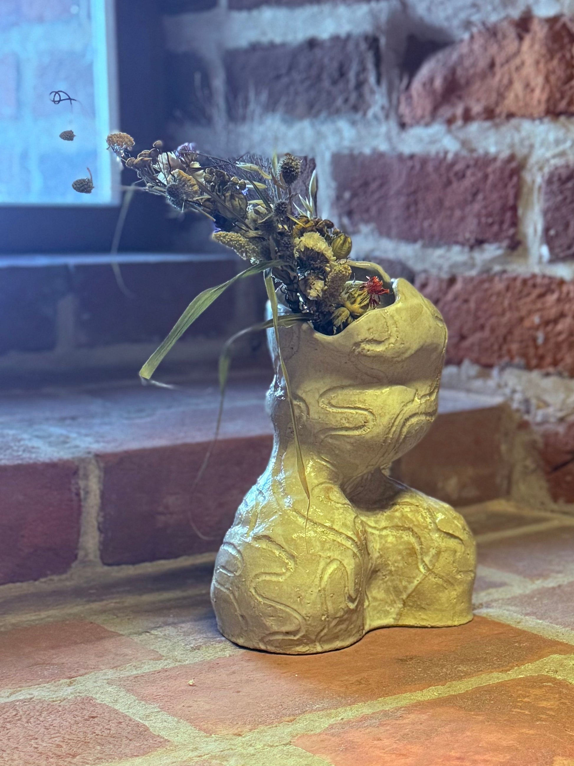 Wazon przypominający popiersie kobiety z kwiatami polnymi